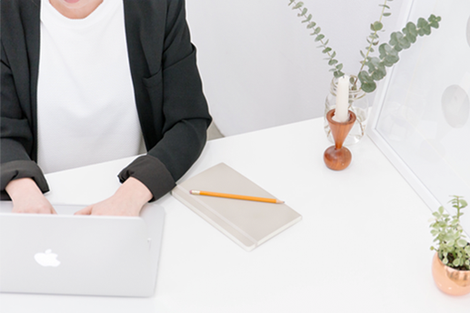 Person at desk with
                        computer and notepad